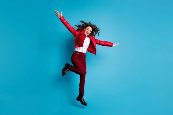 Full Size Foto von optimistischen Mädchen springen tragen rote Jacke Hose Stiefel isoliert auf blauem Hintergrund — Stockfoto