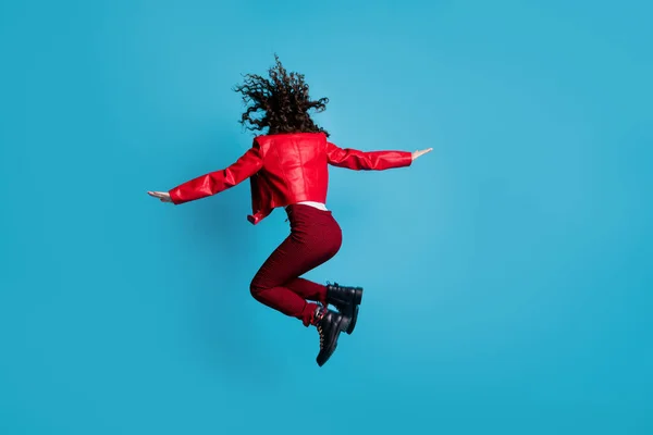 Full size foto posteriore di hooray ragazza salto indossare giacca rossa pantaloni stivali isolati su sfondo blu — Foto Stock