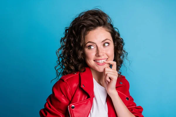 Foto de penteado encaracolado adorável pessoa alegre mordendo unha do dedo olhar espaço vazio isolado no fundo de cor azul — Fotografia de Stock