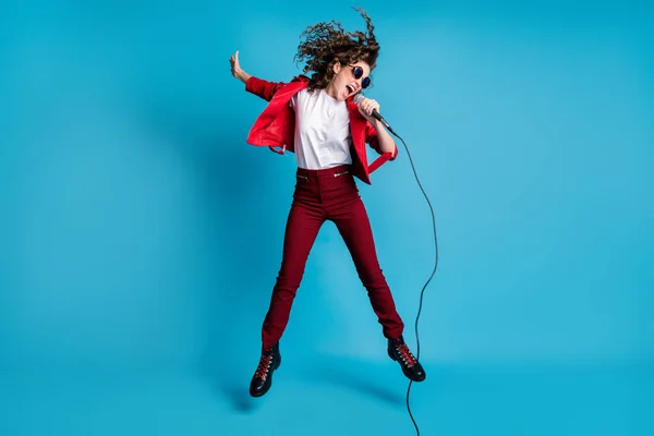 Foto di affascinante divertente giovane signora indossare vestiti rossi occhiali scuri saltare canto canzoni isolate colore blu sfondo — Foto Stock