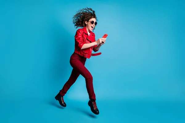 Full length body size view of attractive cheerful trendy girl jumping going using device isolated over bright blue color background — Stock Photo, Image