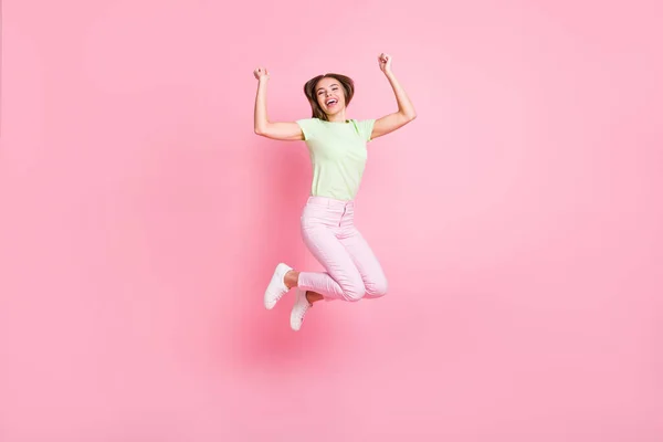 Full size foto van vrolijke zorgeloze jonge meisje springen vuisten omhoog vieren geïsoleerd op roze kleur achtergrond — Stockfoto