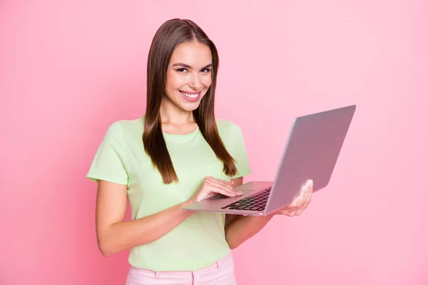 Портрет привлекательной веселой леди руки держать компьютер сияющий улыбка смотреть камеры изолированы на розовый цвет фона — стоковое фото