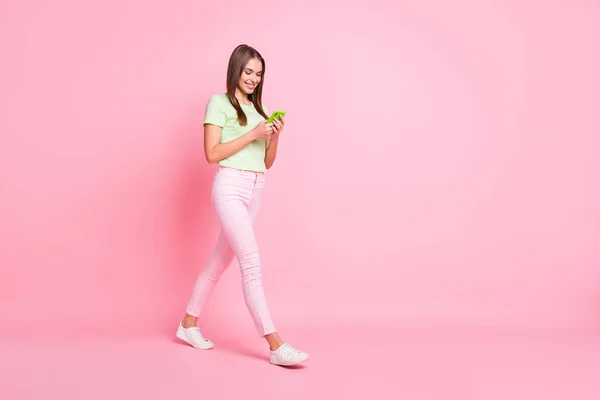 Full storlek profil foto av ganska glad dam promenader skriva kommentar toothy leende isolerad på rosa färg bakgrund — Stockfoto