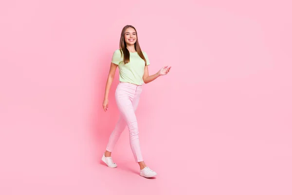 Foto de longitud completa de divertida dulce joven dama usar camiseta verde caminando pastel aislado color rosa fondo —  Fotos de Stock