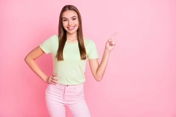 Foto di carino graziosa ragazza vestita verde t-shirt che indica lo spazio vuoto isolato pastello colore rosa sfondo — Foto Stock