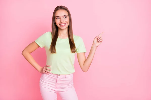 Foto von charmanten süßen jungen Dame tragen grünes T-Shirt lächelnd zeigt auf leeren Raum isoliert pastellrosa Farbe Hintergrund — Stockfoto