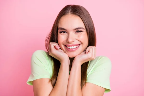 Foto van schattig grappig jong meisje gekleed groen t-shirt armen wangen geïsoleerde pastel roze kleur achtergrond — Stockfoto