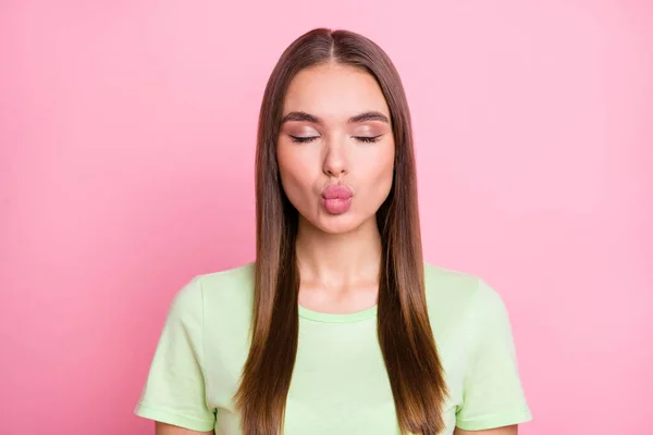 Foto de adorable niña de ensueño vestido verde camiseta labios rellenos ojos cerrados aislados pastel rosa color fondo — Foto de Stock