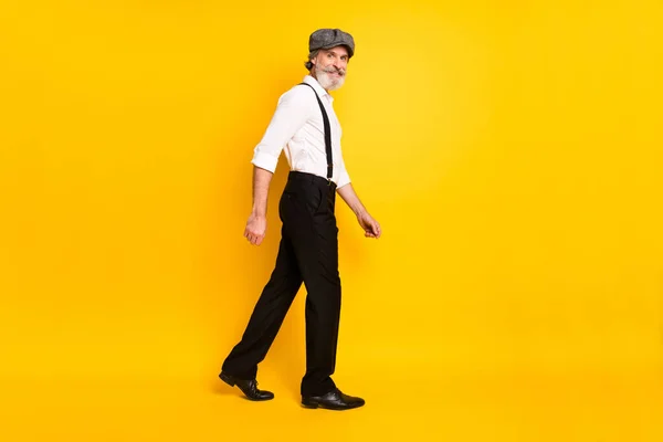 Perfil de cuerpo completo lado de la foto del hombre maduro feliz sonrisa positiva ir caminar paso vacío espacio aislado sobre fondo de color amarillo —  Fotos de Stock