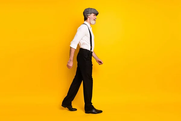 Olgun, yakışıklı bir adamın tam vücut profili fotoğrafı sarı arkaplan üzerinde izole bir şekilde boş bir alanda yürü. — Stok fotoğraf