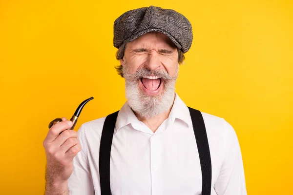 Foto portret van een man met baard lachen in retro outfit roken houten pijp glimlachen geïsoleerde levendige gele kleur achtergrond — Stockfoto