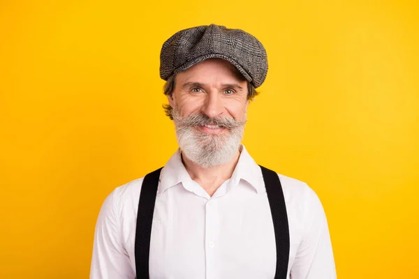 รูปภาพของชายหนวดสวมหมวกสีเทาแขวนเสื้อยืด ยิ้มมีความสุขโดดเดี่ยวบนพื้นหลังสีเหลืองสดใส — ภาพถ่ายสต็อก