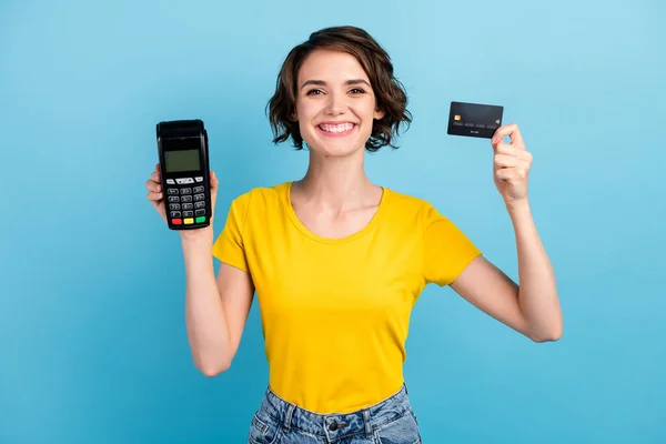 Фото чарівного промоутера дівчата показують кредитну картку термінал носіння жовтої футболки ізольований синій колір фону — стокове фото
