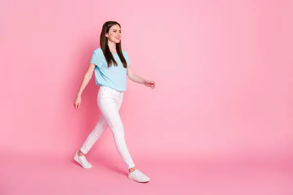 Full längd profil sida foto av ganska härlig flicka gå tomt utrymme slitage sneakers isolerade över rosa färg bakgrund — Stockfoto
