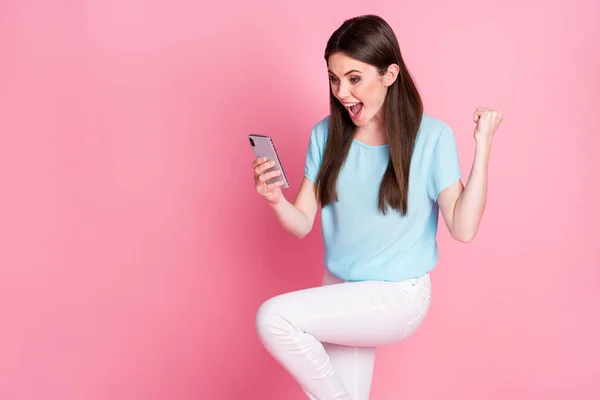 Fotografie extatické dívka použít smartphone zvednout pěst křik nosit modré bílé kalhoty izolované pastelové barvy pozadí — Stock fotografie