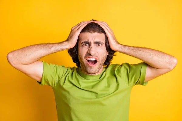 Fénykép a zavaros vesztes fickó tenyér fej nyitott száj viselni zöld póló izolált sárga színű háttér — Stock Fotó