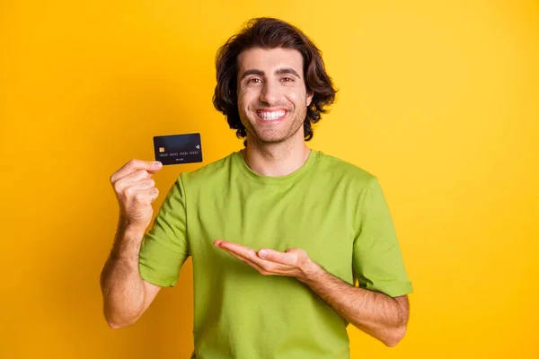 Portret foto van lachende vrolijke man houden bank credit card glimlachen geïsoleerd op fel gele kleur achtergrond — Stockfoto
