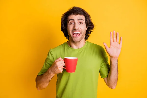Portré fotó az ember tartja csésze kávé integetett kézzel köszöntés elszigetelt élénk sárga háttér — Stock Fotó