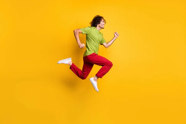 Lunghezza intera dimensione del corpo profilo laterale foto di salto uomo in esecuzione veloce sorridente isolato su vivido sfondo di colore giallo — Foto Stock