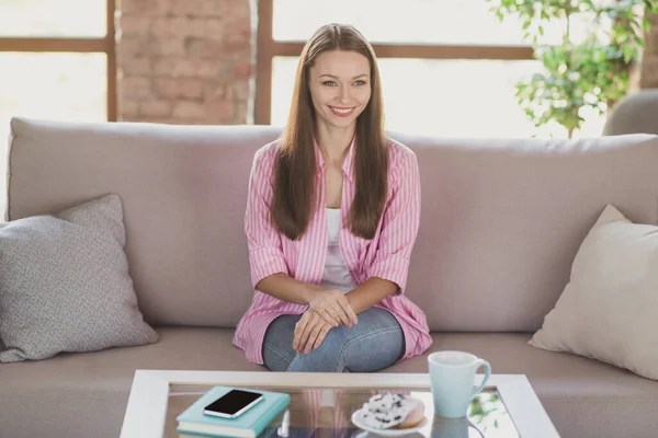Fotografie rozkošné okouzlující mladá dáma nosit růžovou košili sedí gauč usměvavý vnitřní pokoj domácí dům — Stock fotografie