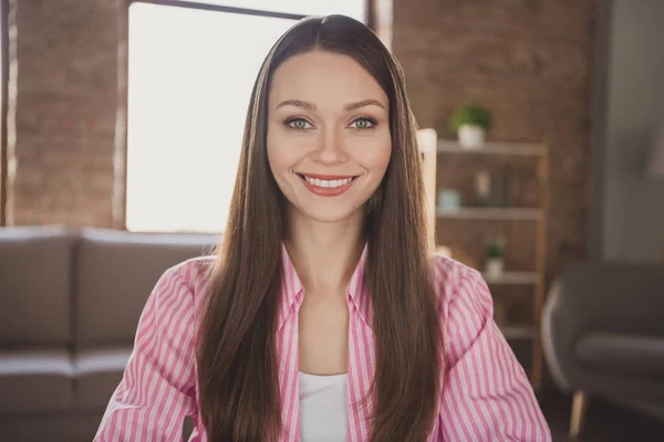 Foto de la impresionante morena de pelo joven mujer usar camisa de rayas rosa buen humor sonrisa en el interior de la casa de la sala de estar — Foto de Stock