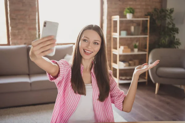 Фото привлекательной молодой женщины держать руку показать жест сделать селфи внутри дома квартиру в помещении — стоковое фото