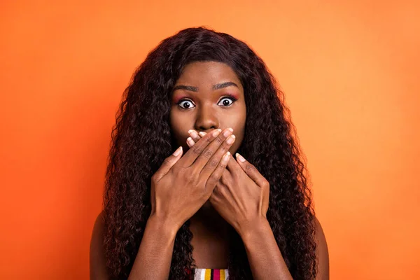 Foto van geschokt verbaasd verbaasd Afrikaanse vrouw cover close mond met handen schuldig geïsoleerd op oranje kleur achtergrond — Stockfoto