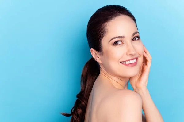 Foto da jovem mulher feliz sorriso positivo mão toque bochecha olhar vazio espaço spa isolado sobre azul cor fundo — Fotografia de Stock