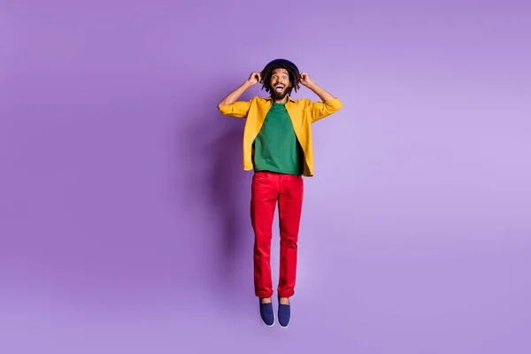 Foto de comprimento total de bonito engraçado pele escura cara vestido camisa amarela braços saltando alto isolado cor roxa fundo — Fotografia de Stock