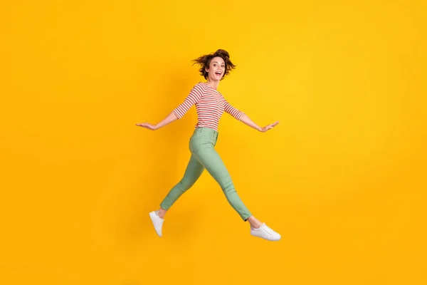 Volledige lengte lichaamsgrootte profiel zijaanzicht van mooie vrolijke meisje springen gaan geïsoleerd over helder gele kleur achtergrond — Stockfoto