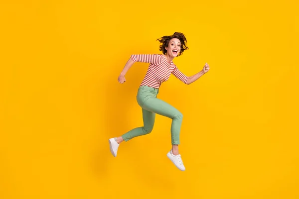 Retrato de comprimento total de agradável satisfeito jovem pressa correr pular punhos boca aberta isolada no fundo de cor amarela — Fotografia de Stock