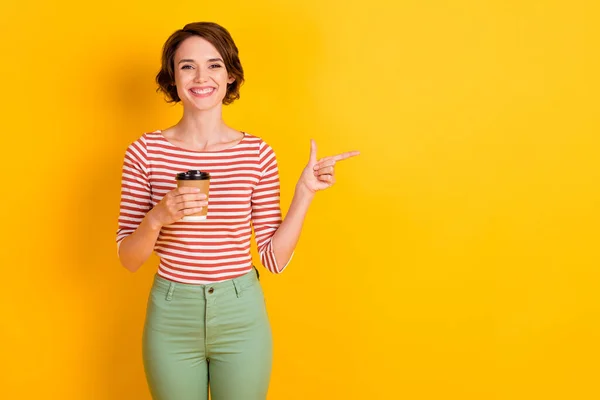 Retrato de atractiva dama positiva sostiene el dedo de la bebida indican espacio vacío aislado en el fondo de color amarillo — Foto de Stock