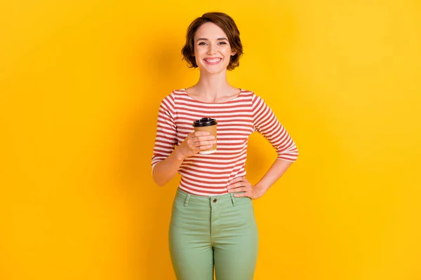 Foto de persona satisfecha sonrisa mantenga café poner brazo en la cintura aislado sobre fondo de color amarillo vivo — Foto de Stock