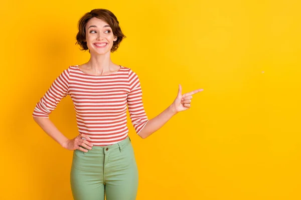 Retrato de la bella dama mirando vacío dedo de la punta del espacio poner el brazo en la cintura aislado en el fondo de color amarillo vibrante —  Fotos de Stock