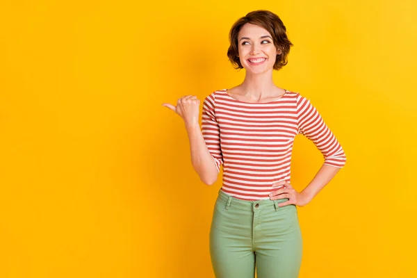 Portrait photo of curious happy girl with bob hair pointing looking at copyspace smiling isolated on vibrant yellow color background — Stock Photo, Image