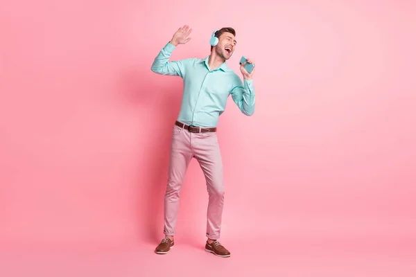 Foto de comprimento total de homem feliz louco cantar segurar fone de ouvido desgaste bom humor vestir roupas formais isolados no fundo cor-de-rosa — Fotografia de Stock