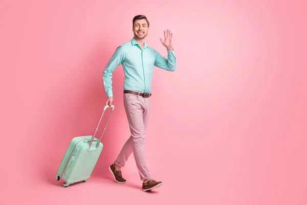 Full size profil boczne zdjęcie brunetka człowiek go fala bagaż trzymać nosić ciemny morski koszula różowe spodnie izolowane na pastelowym tle kolor — Zdjęcie stockowe