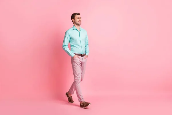 Full size profile side photo of young happy cheerful smiling man go walk hold hands in pockets isolated on pink color background — Stock Photo, Image