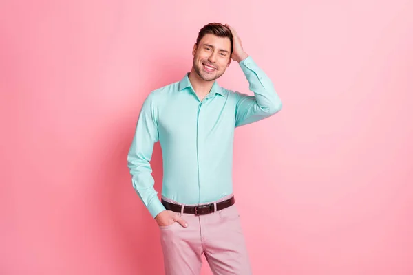 Foto retrato de homem bonito tocando penteado vestindo camisa azul oink calças isoladas no fundo cor de rosa pastel — Fotografia de Stock