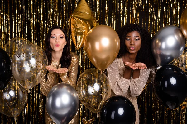 Photo of optimistic brunette ladies blow kiss balloon wear nice dresses isolated on bright gold color background — Stock Photo, Image