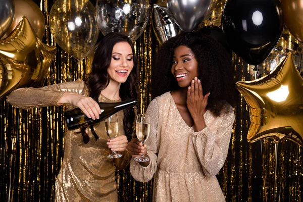 Fénykép a lenyűgöző boldog hölgyek viselni flitterek ruha öntsük poharak pezsgő vidám elszigetelt ragyogás fényes háttér — Stock Fotó