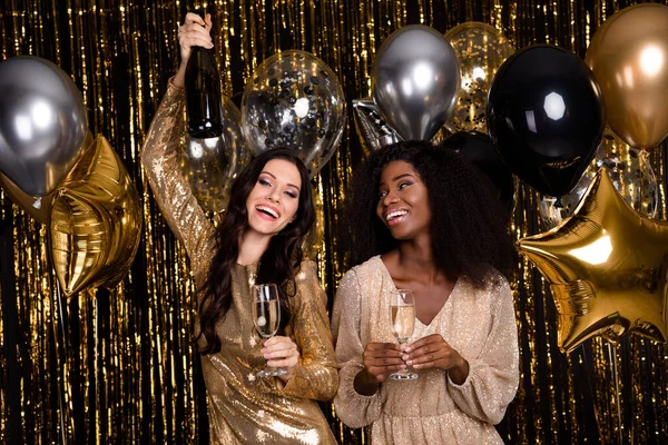 Photo of two optimistic brunette ladies stand drink wear dress isolated on gold color background — Stock Photo, Image