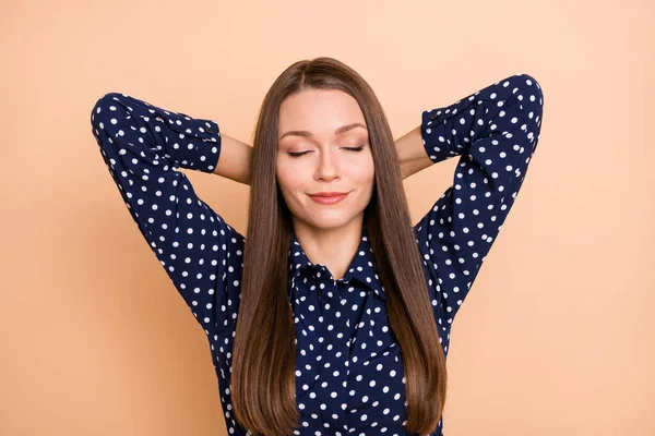 Foto de adorable niña de ensueño vestido blusa punteada ojos cerrados brazos detrás de la cabeza aislado color beige fondo — Foto de Stock