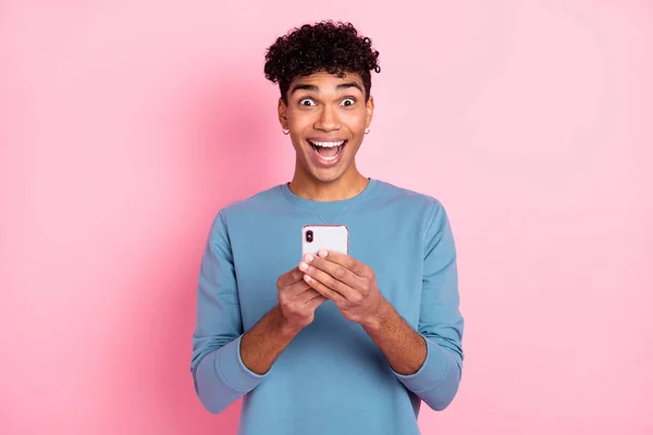 Foto retrato de un joven sorprendido mirando fijamente internet teléfono celular aislado sobre fondo de color rosa pastel — Foto de Stock