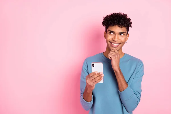 Foto de optimista chico morena agradable mirada espacio vacío escribir ropa de teléfono suéter azul aislado sobre fondo de color rosa pastel — Foto de Stock