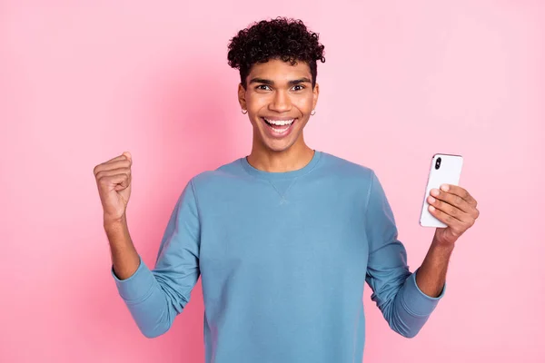Portrait photo de jeune homme gardant smartphone geste comme gagnant riant isolé sur fond de couleur rose pastel — Photo
