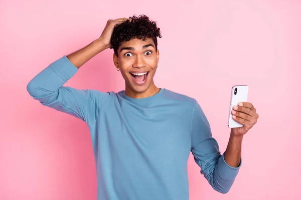 Foto van jonge opgewonden afro man gelukkig positieve glimlach verbaasd geschokt verrast gebruik mobiele telefoon geïsoleerd over roze kleur achtergrond — Stockfoto