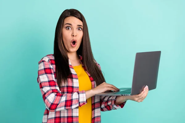 Foto de mulher jovem surpreso segurar laptop usar camisa xadrez isolado no fundo cor pastel teal — Fotografia de Stock