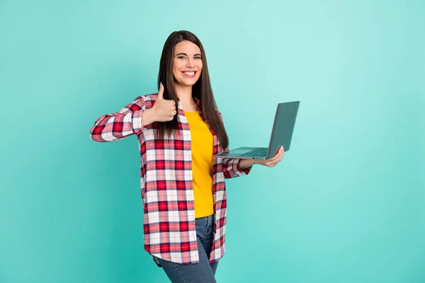 幸せな若い女性の写真を作る親指アップは、品質をお勧めしますホールドノートパソコンは、鉄の色の背景に隔離 — ストック写真